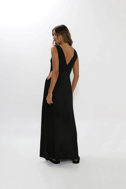 Fashion model showing back of black maxi dress with low-cut back.